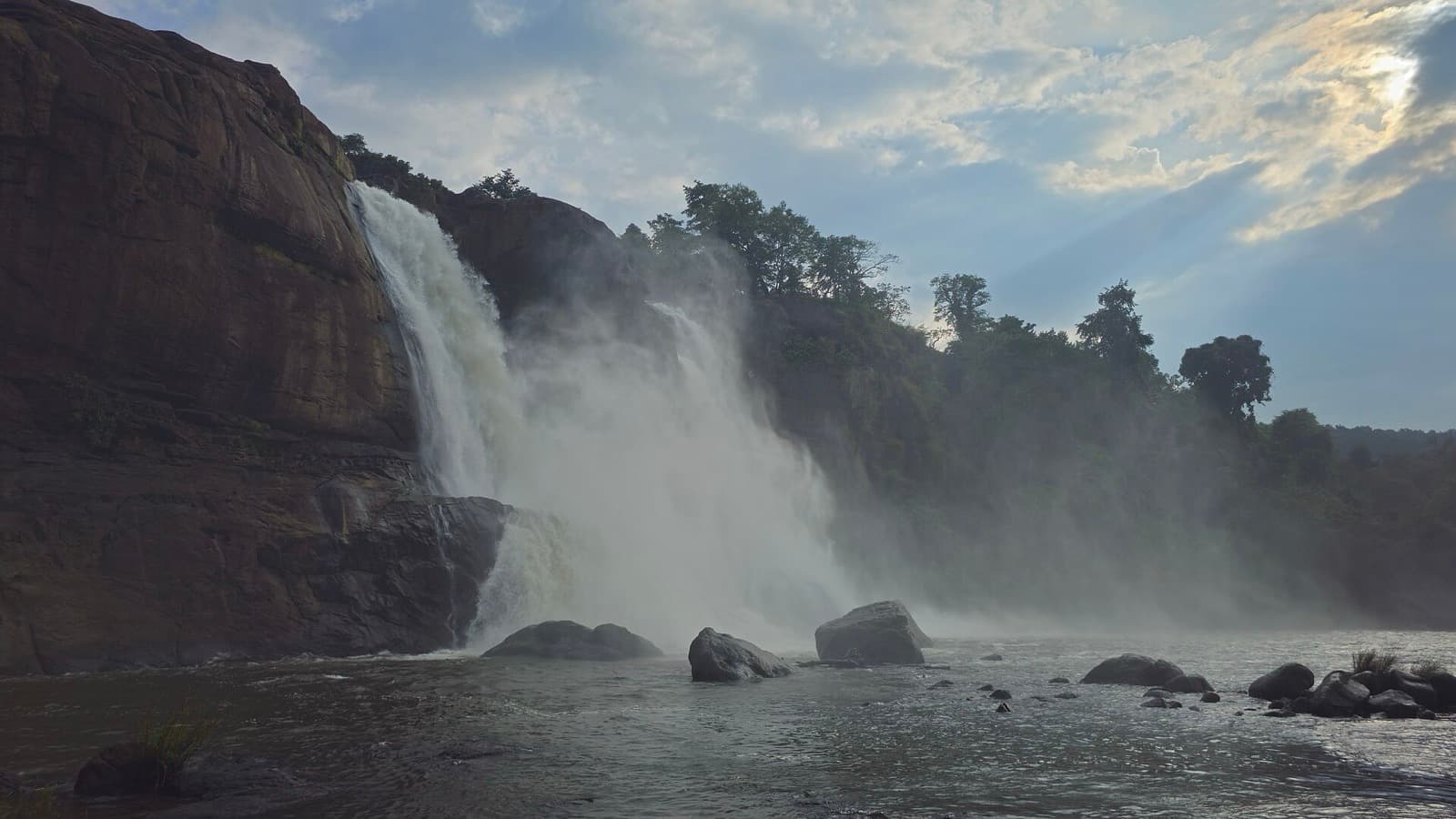Wide waterfall cascading over rocks surrounded by green forest