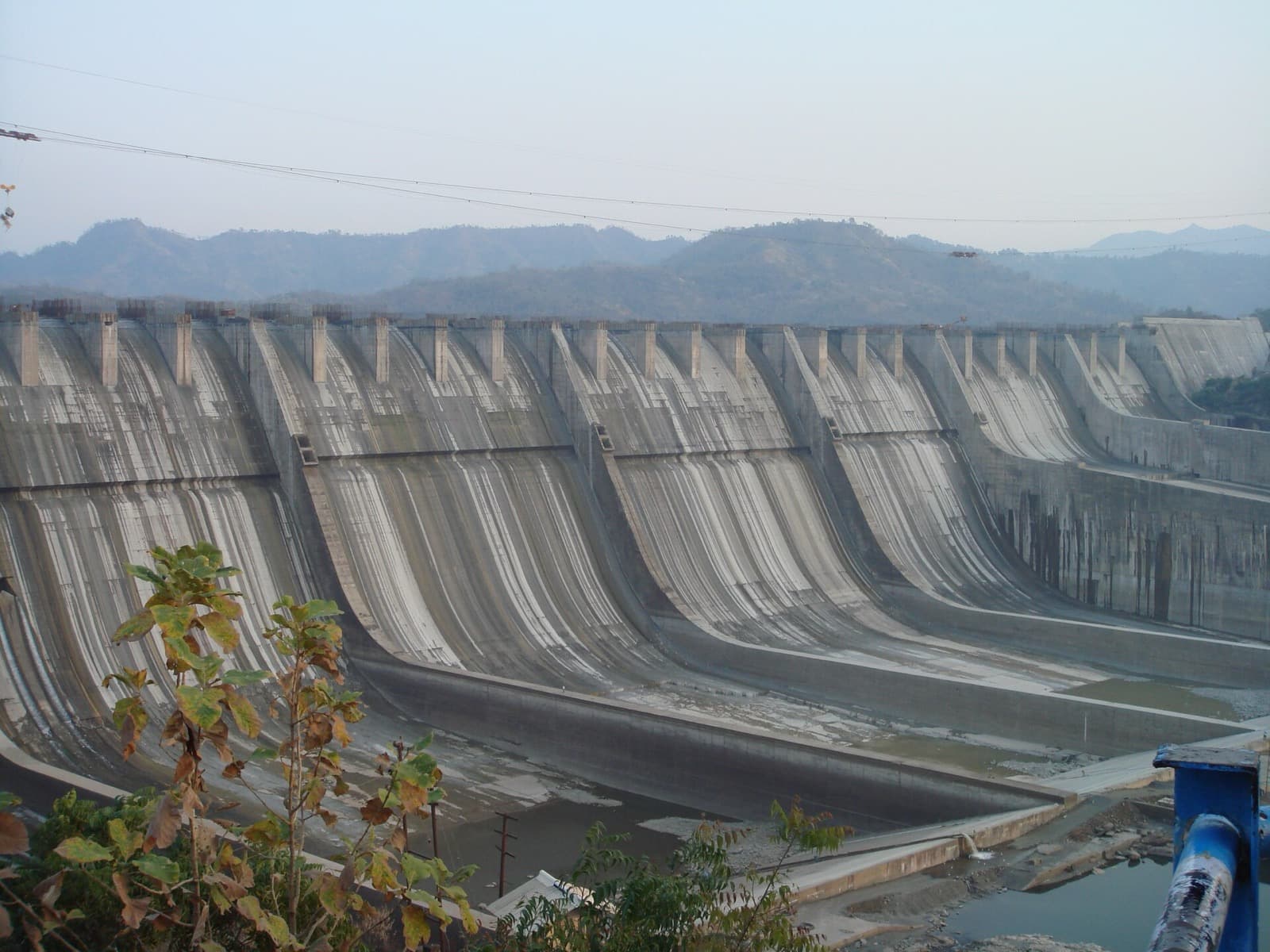 The concrete spillway of the Sardar Sarovar Dam with hills behind it